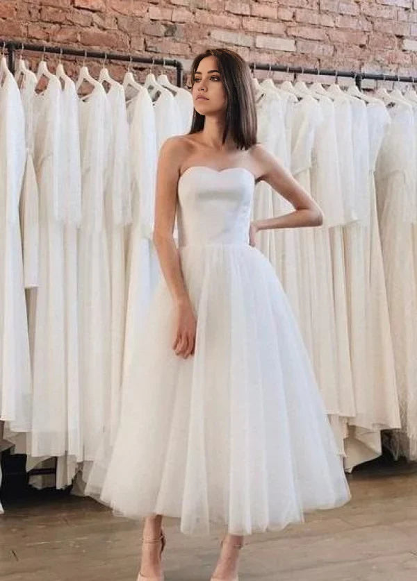 Vestido de novia corto de tul con corte A, espalda descubierta, sin tirantes y largo hasta la rodilla